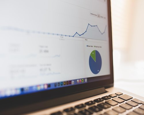 Researcher reviewing market graphs and financial data on multiple screens